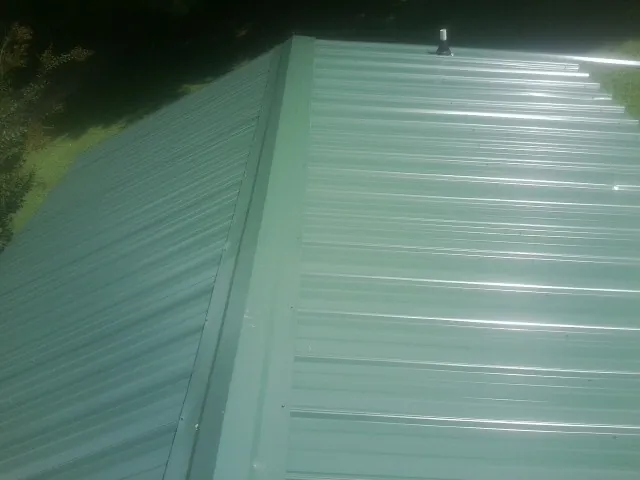 New green metal panels meeting at the ridge of a roof — Flat Roof Repair work by our crew in North Bay