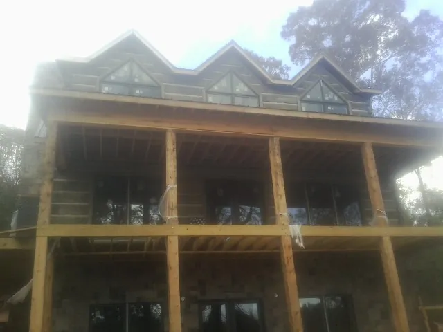 Dormers and porch framing on a large log home under construction — Roof Coating work by our crew in North Bay