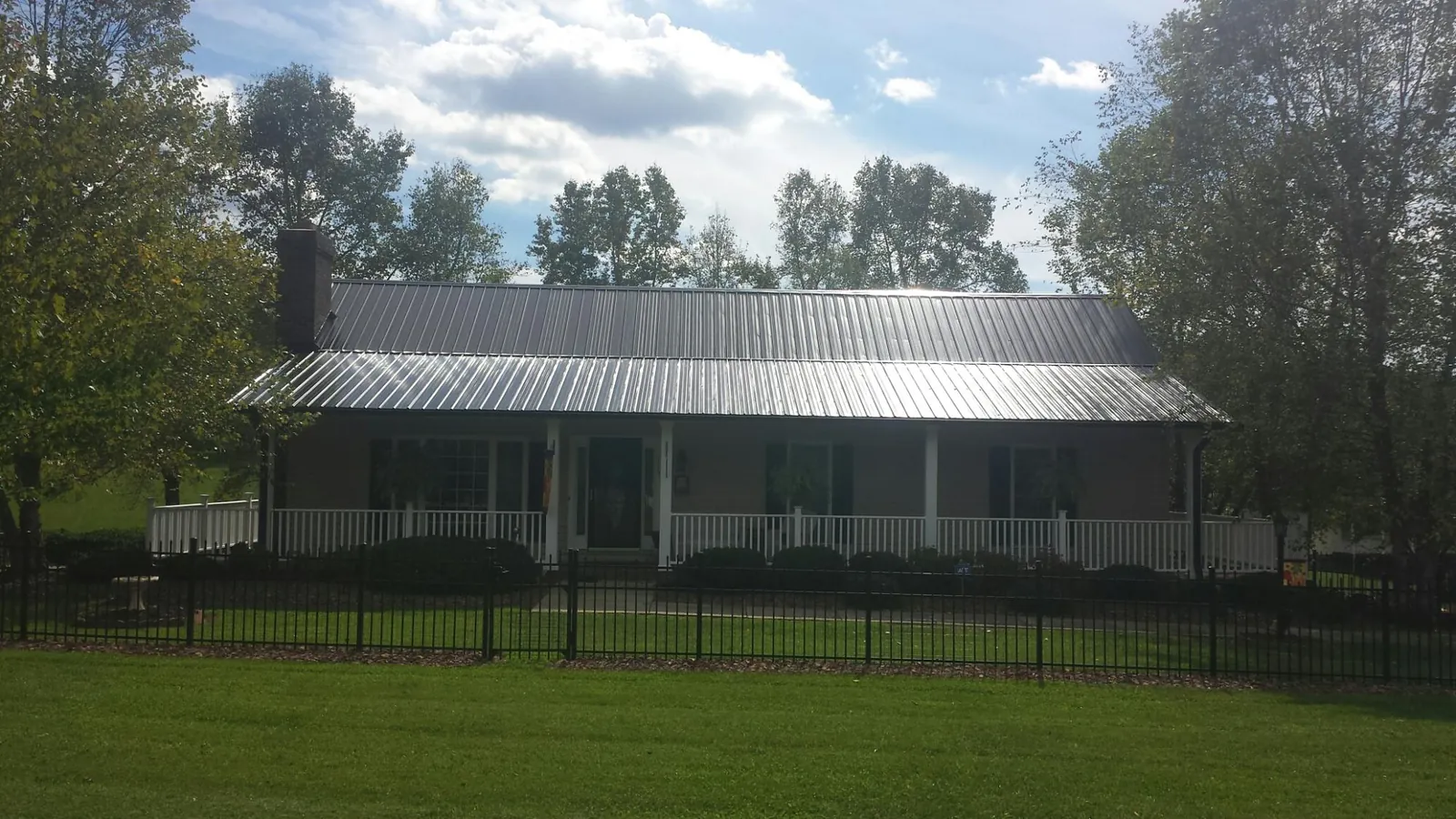 Gray metal roof on a brick ranch with a full width front porch — Gutter Guard Installation work by our crew in North Bay