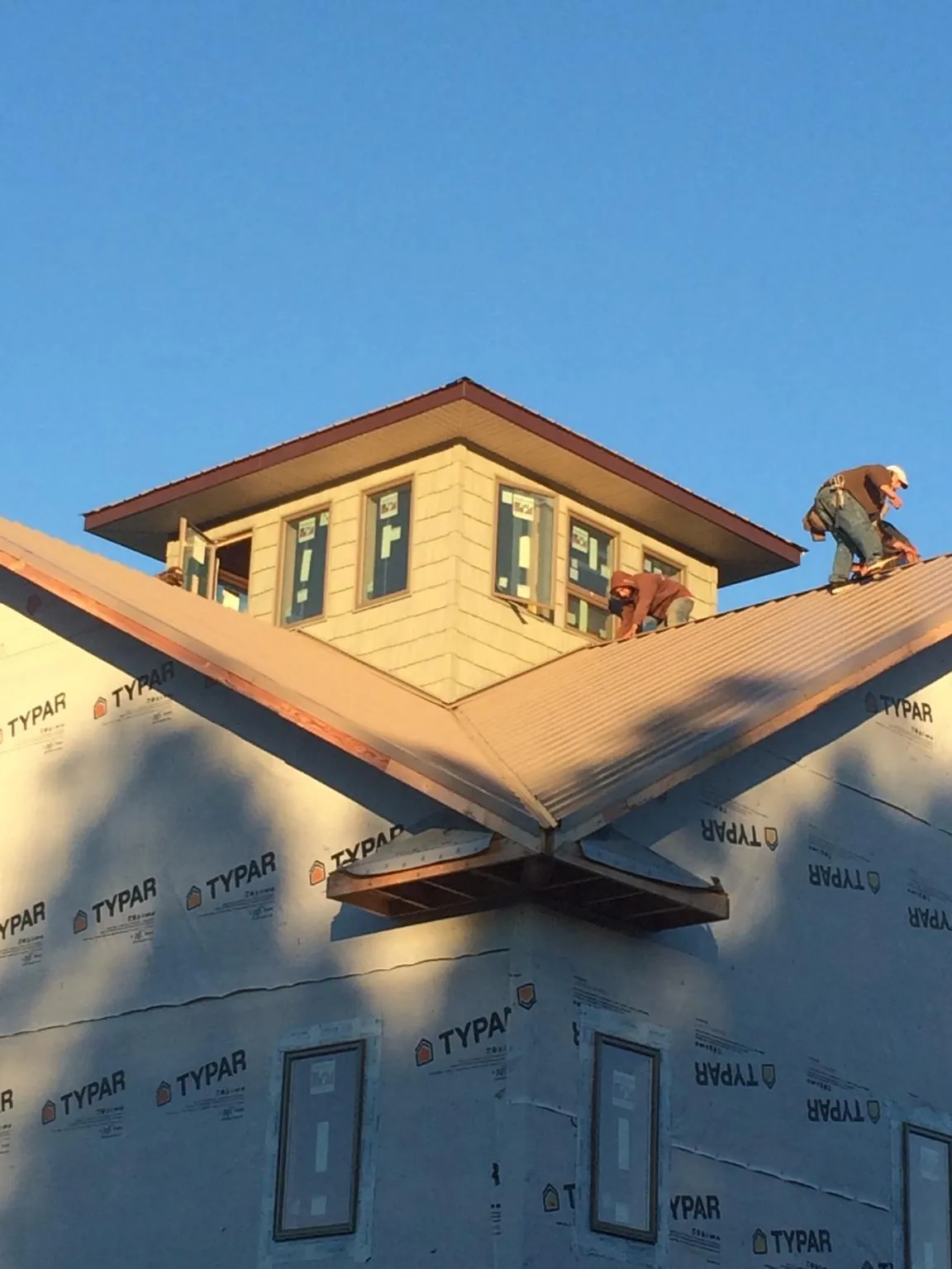 Roofers working around a rooftop cupola on a new metal roof at sunset — Roof Waterproofing in North Bay by Roofing Brothers